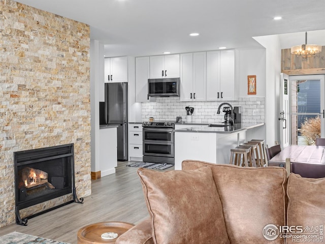 1437 Raven Cir Unit H, Estes Park, CO 80517 - kitchen featuring stainless steel appliances, light wood-style floors, white cabinetry, decorative backsplash, and recessed lighting