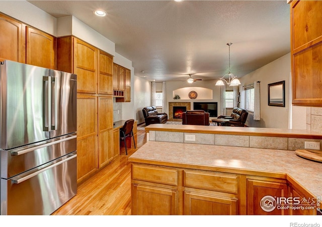 1414 Sheep Creek Ct, Fort Collins, CO 80526 - kitchen with high end fridge, light countertops, a lit fireplace, light wood finished floors, and open floor plan