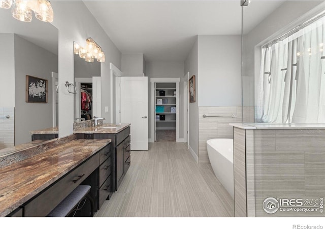 5031 Prairie Lark Ln, Severance, CO 80615 - bathroom featuring a walk in closet, a freestanding tub, vanity, and a chandelier
