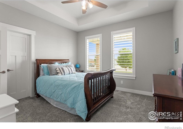 5031 Prairie Lark Ln, Severance, CO 80615 - carpeted bedroom featuring a tray ceiling, baseboards, and a ceiling fan