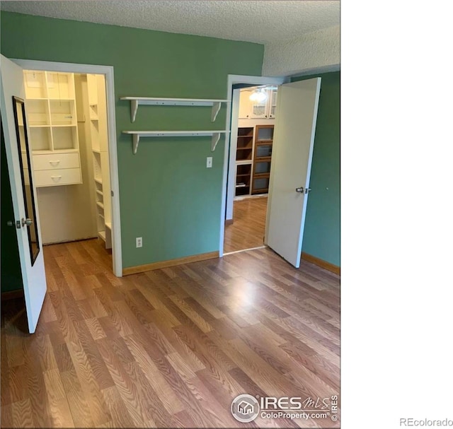 3250 Oneal Cir Unit 14, Boulder, CO 80301 - unfurnished bedroom with wood finished floors, a walk in closet, a closet, and a textured ceiling
