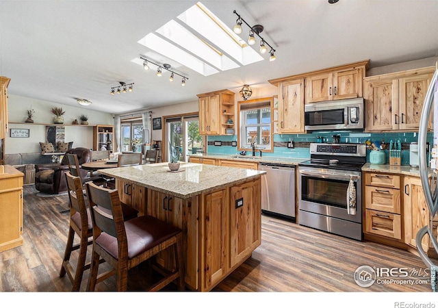 10635 County Road 24, Fort Lupton, CO 80621 - kitchen with appliances with stainless steel finishes, track lighting, a skylight, a center island, and wood finished floors
