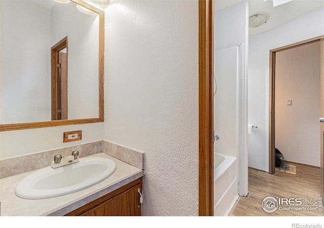 10635 County Road 24, Fort Lupton, CO 80621 - bathroom featuring vanity, wood finished floors, a bath, and a textured wall