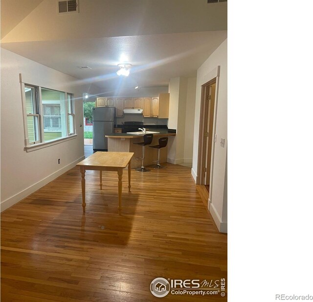 936 Parkview St, Louisville, CO 80027 - kitchen featuring freestanding refrigerator, under cabinet range hood, a peninsula, baseboards, and light wood-style floors