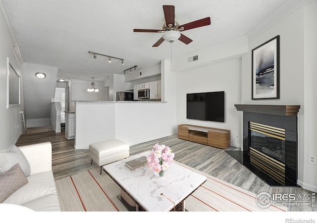 1837 Spaulding Cir, Superior, CO 80027 - living room featuring wood finished floors, a textured ceiling, ceiling fan, a tile fireplace, and ornamental molding