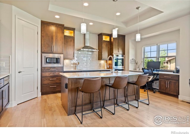 5112 Daylight Ct, Fort Collins, CO 80528 - kitchen with appliances with stainless steel finishes, wall chimney range hood, light wood-style floors, a raised ceiling, and recessed lighting