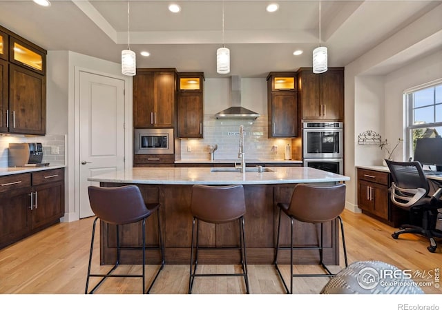 5112 Daylight Ct, Fort Collins, CO 80528 - kitchen featuring wall chimney range hood, stainless steel appliances, a raised ceiling, light wood-type flooring, and recessed lighting