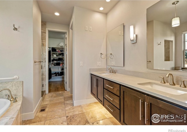 5112 Daylight Ct, Fort Collins, CO 80528 - bathroom with double vanity, a bath, baseboards, stone tile flooring, and recessed lighting
