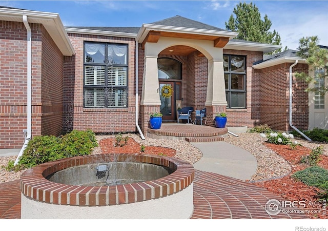 13 Blue Heron Dr, Thornton, CO 80241 - view of exterior entry with brick siding, a shingled roof, and covered porch