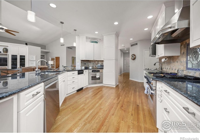13 Blue Heron Dr, Thornton, CO 80241 - kitchen with wall chimney exhaust hood, stainless steel appliances, a sink, decorative backsplash, and lofted ceiling