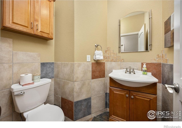13 Blue Heron Dr, Thornton, CO 80241 - bathroom featuring tile walls, vanity, toilet, and a wainscoted wall