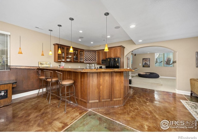 13 Blue Heron Dr, Thornton, CO 80241 - kitchen featuring freestanding refrigerator, glass insert cabinets, stainless steel microwave, brown cabinetry, and a peninsula