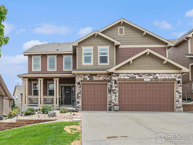 2163 Longfin Dr, Windsor, CO 80550 - craftsman-style home featuring driveway, a porch, an attached garage, and stone siding