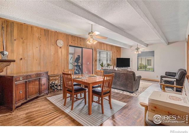 2525 S Dayton Way Unit 2301, Denver, CO 80231 - dining area featuring ceiling fan, beamed ceiling, wood walls, light wood finished floors, and a textured ceiling