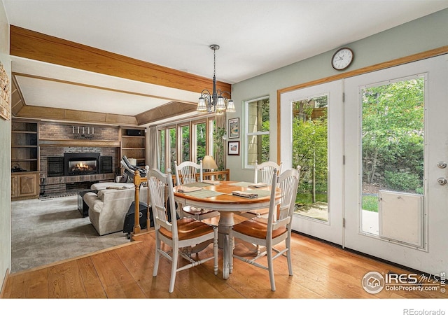 3441 W Dartmouth Ave, Denver, CO 80236 - dining area with light wood-style flooring, a brick fireplace, a chandelier, and built in shelves