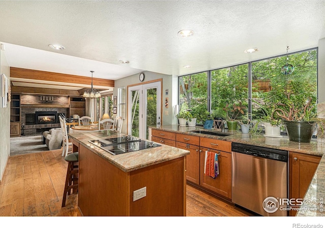 3441 W Dartmouth Ave, Denver, CO 80236 - kitchen with stainless steel dishwasher, a sink, black electric cooktop, brown cabinetry, and healthy amount of natural light
