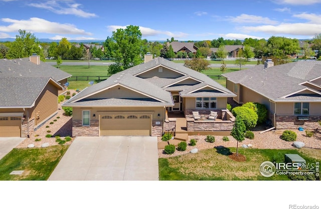 6728 Spanish Bay Dr, Windsor, CO 80550 - view of front facade with driveway, stone siding, an attached garage, and stucco siding