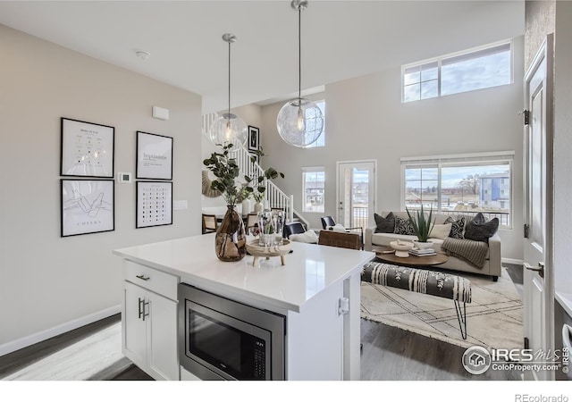 945 Abbott Ln Unit 5, Fort Collins, CO 80524 - kitchen featuring stainless steel microwave, light wood-style flooring, white cabinets, baseboards, and a high ceiling