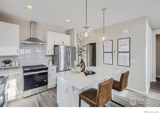 945 Abbott Ln Unit 5, Fort Collins, CO 80524 - kitchen featuring stainless steel appliances, wall chimney range hood, light wood-style flooring, light countertops, and white cabinetry