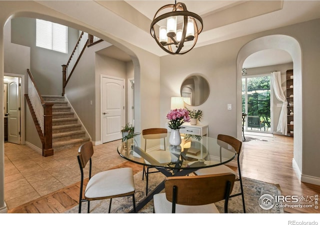 2315 Haymeadow Way, Fort Collins, CO 80525 - dining room featuring arched walkways, a chandelier, baseboards, stairway, and a raised ceiling