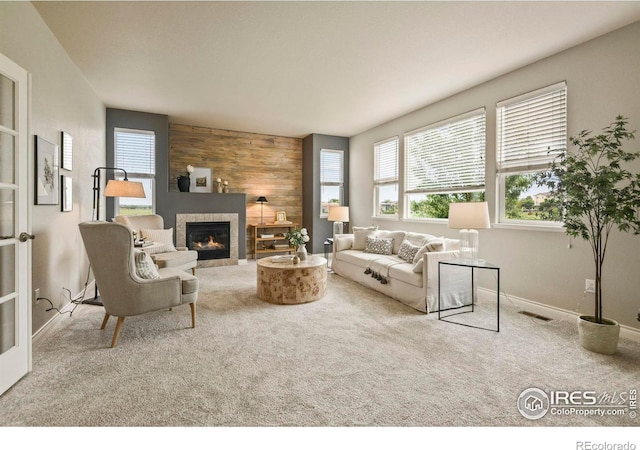 2315 Haymeadow Way, Fort Collins, CO 80525 - carpeted living area with a tiled fireplace, healthy amount of natural light, wood walls, and baseboards