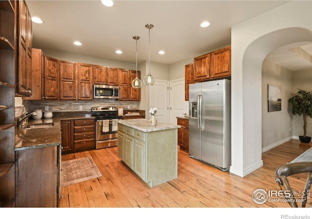 2315 Haymeadow Way, Fort Collins, CO 80525 - kitchen featuring stainless steel appliances, a sink, arched walkways, tasteful backsplash, and a kitchen island