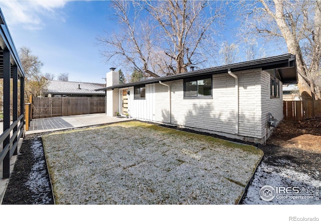 2435 S Meade St, Denver, CO 80219 - rear view of property with a patio, a fenced backyard, a chimney, and brick siding