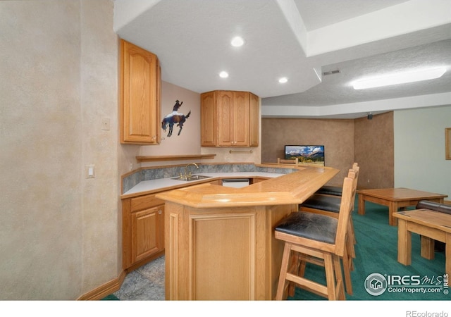 6239 Ashcroft Rd, Greeley, CO 80634 - kitchen with a sink, light countertops, a kitchen bar, light brown cabinets, and recessed lighting