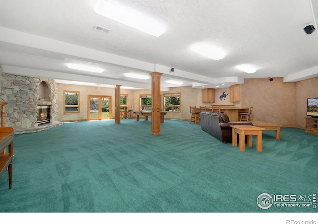 6239 Ashcroft Rd, Greeley, CO 80634 - living room featuring light carpet, a textured ceiling, a fireplace, and decorative columns