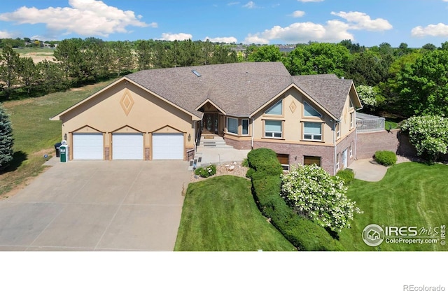 6239 Ashcroft Rd, Greeley, CO 80634 - view of front facade featuring a garage, stucco siding, concrete driveway, a front yard, and brick siding
