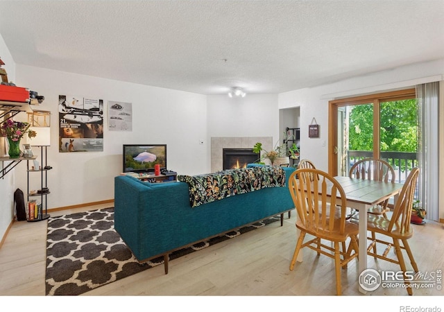 2802 Sundown Ln Unit 102, Boulder, CO 80303 - living room featuring wood finished floors, a tiled fireplace, a textured ceiling, and baseboards