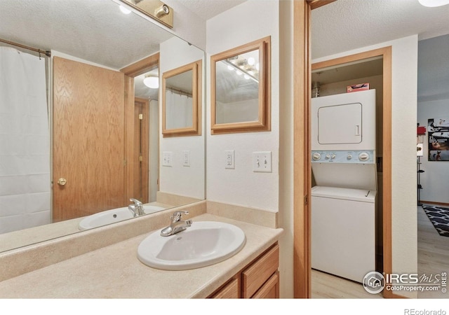 2802 Sundown Ln Unit 102, Boulder, CO 80303 - full bath with stacked washing machine and dryer, a textured ceiling, vanity, and wood finished floors
