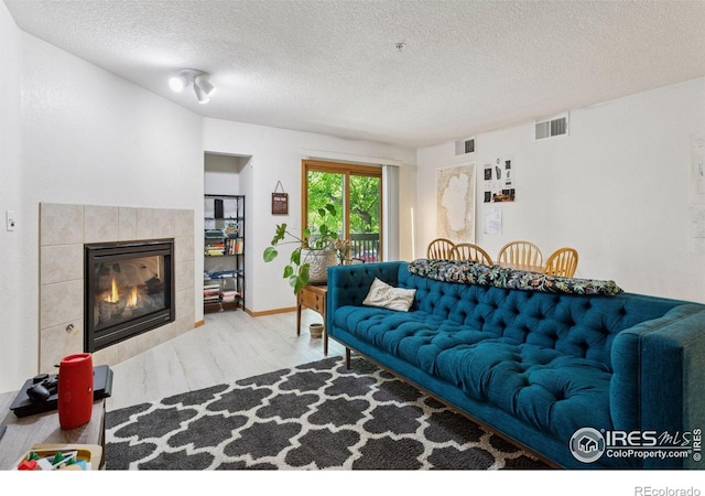 2802 Sundown Ln Unit 102, Boulder, CO 80303 - living room featuring wood finished floors, a textured ceiling, and a tile fireplace
