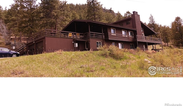 730 Spring St, Estes Park, CO 80517 - view of front of home with a chimney, a wooden deck, and a view of trees