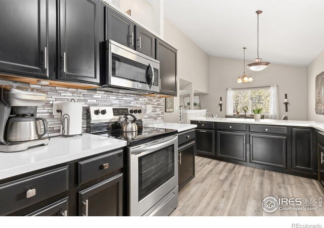 9930 Cascade St, Firestone, CO 80504 - kitchen featuring appliances with stainless steel finishes, tasteful backsplash, vaulted ceiling, dark cabinets, and light wood-style flooring