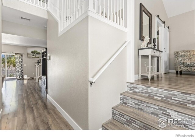 9930 Cascade St, Firestone, CO 80504 - stairway featuring a barn door, baseboards, a high ceiling, and wood finished floors