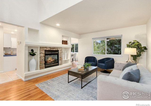 1382 Warbler St, Loveland, CO 80537 - living room with light wood-style floors, a stone fireplace, and recessed lighting