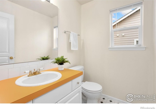 1382 Warbler St, Loveland, CO 80537 - bathroom featuring toilet, vanity, decorative backsplash, baseboards, and tile patterned flooring