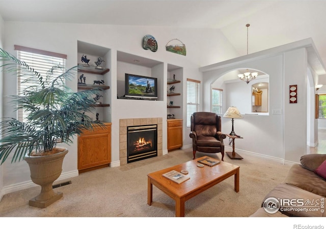 6911 W 22nd St, Greeley, CO 80634 - living room with built in features, lofted ceiling, light carpet, arched walkways, and a tile fireplace