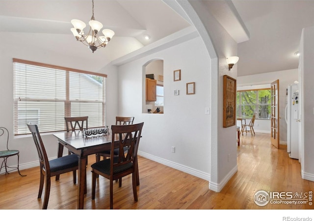 6911 W 22nd St, Greeley, CO 80634 - dining space featuring arched walkways, a chandelier, light wood-style floors, baseboards, and vaulted ceiling