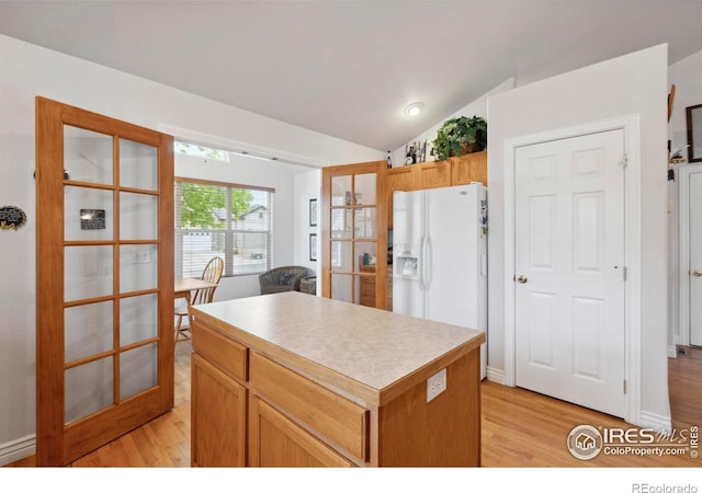 6911 W 22nd St, Greeley, CO 80634 - kitchen featuring white refrigerator with ice dispenser, light wood finished floors, french doors, a center island, and vaulted ceiling