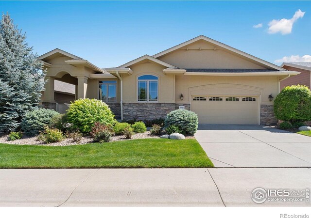 6787 Spanish Bay Dr, Windsor, CO 80550 - view of front of home featuring stone siding, an attached garage, stucco siding, and concrete driveway