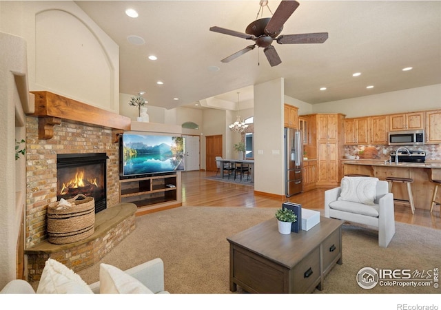 6787 Spanish Bay Dr, Windsor, CO 80550 - living area featuring light wood-style floors, a chandelier, recessed lighting, a brick fireplace, and a ceiling fan
