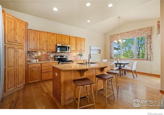 6787 Spanish Bay Dr, Windsor, CO 80550 - kitchen featuring appliances with stainless steel finishes, a sink, wood finished floors, lofted ceiling, and a kitchen bar