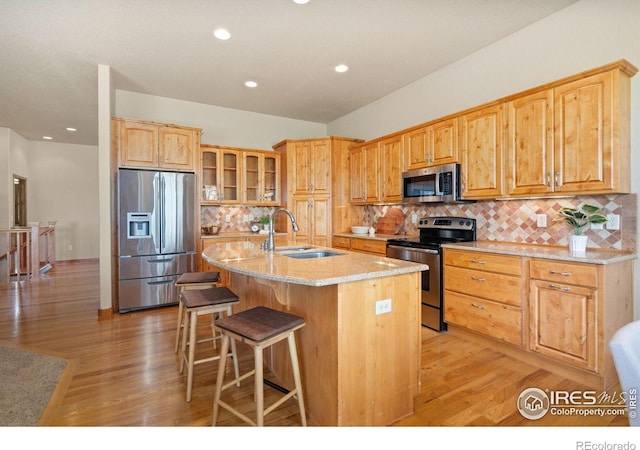 6787 Spanish Bay Dr, Windsor, CO 80550 - kitchen with stainless steel appliances, a sink, light stone countertops, light wood finished floors, and recessed lighting