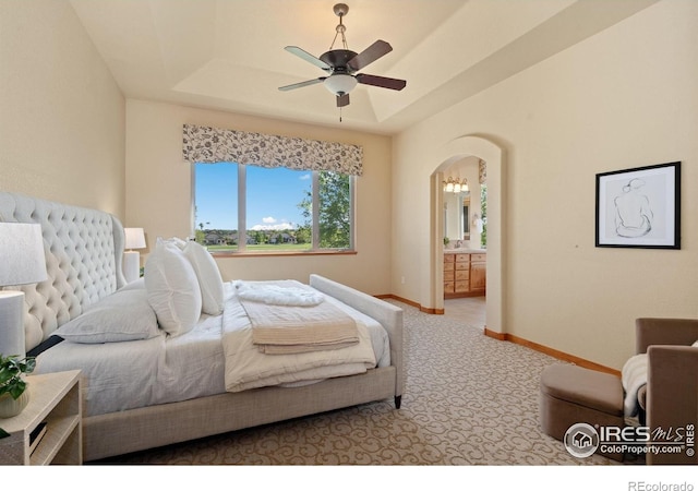 6787 Spanish Bay Dr, Windsor, CO 80550 - carpeted bedroom featuring arched walkways, ensuite bath, a raised ceiling, baseboards, and a ceiling fan