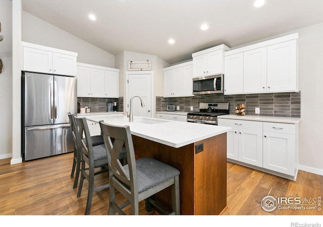 7025 Meadow Rain Way, Wellington, CO 80549 - kitchen featuring appliances with stainless steel finishes, a sink, light countertops, a breakfast bar area, and white cabinetry