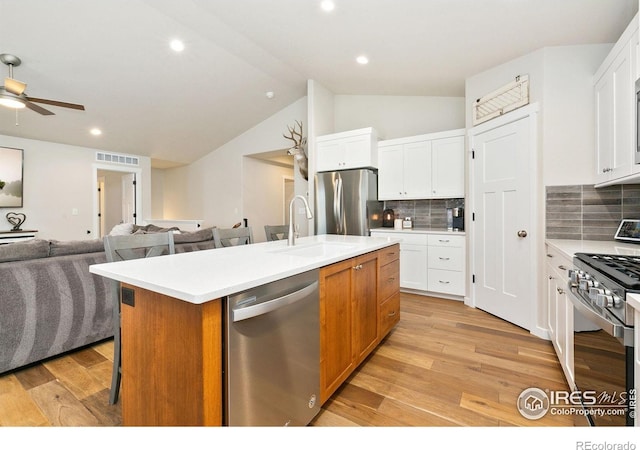 7025 Meadow Rain Way, Wellington, CO 80549 - kitchen with appliances with stainless steel finishes, a sink, open floor plan, a kitchen island with sink, and light countertops