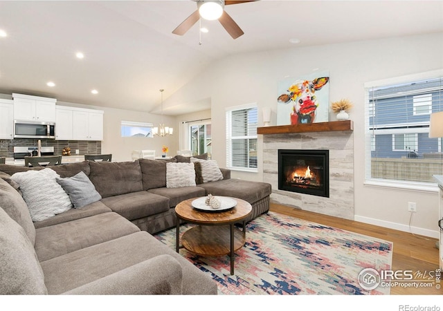7025 Meadow Rain Way, Wellington, CO 80549 - living room with light wood-type flooring, a chandelier, a fireplace, a ceiling fan, and vaulted ceiling