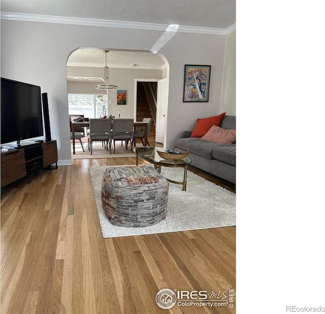 731 Bowen St, Longmont, CO 80501 - living room with arched walkways, crown molding, wood finished floors, a chandelier, and baseboards
